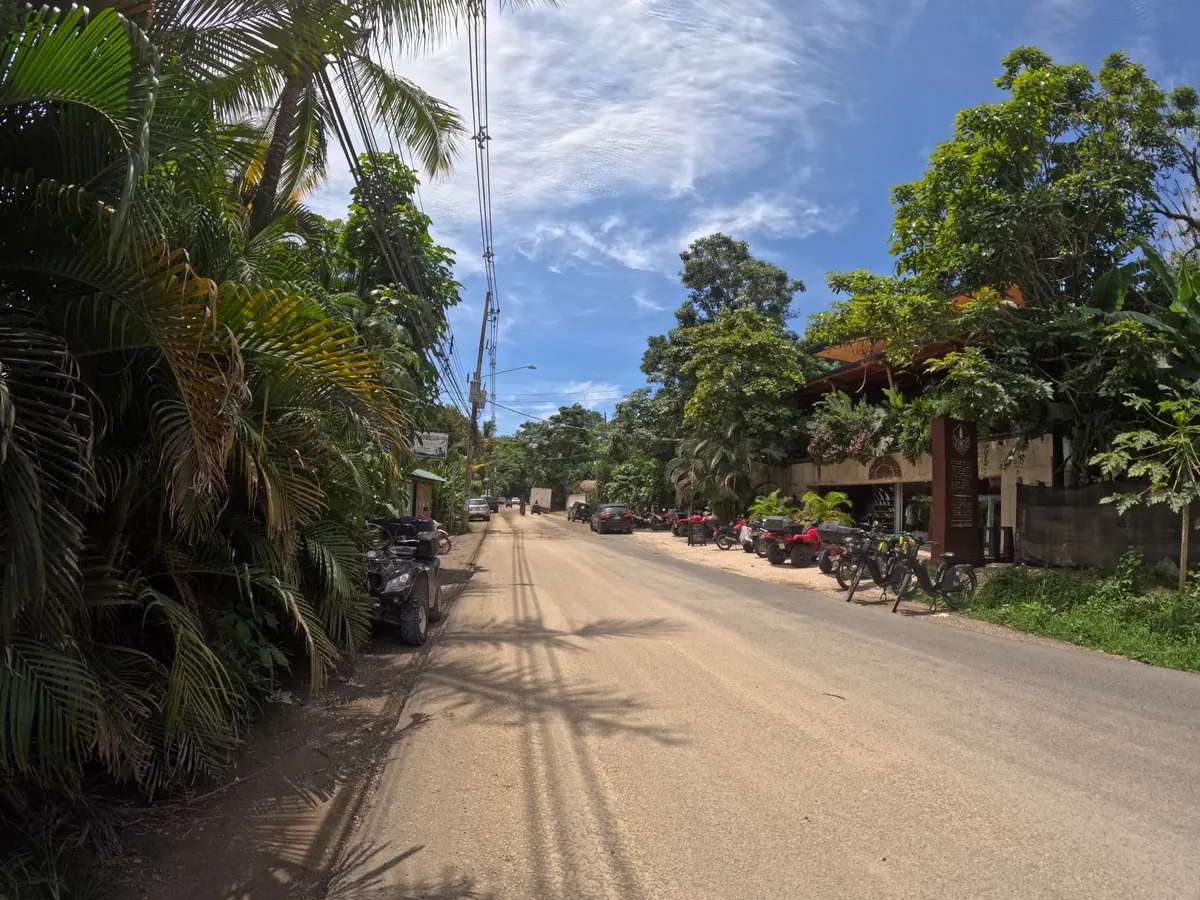 The paved main street through Santa Teresa, lined with palms and parked motorbikes