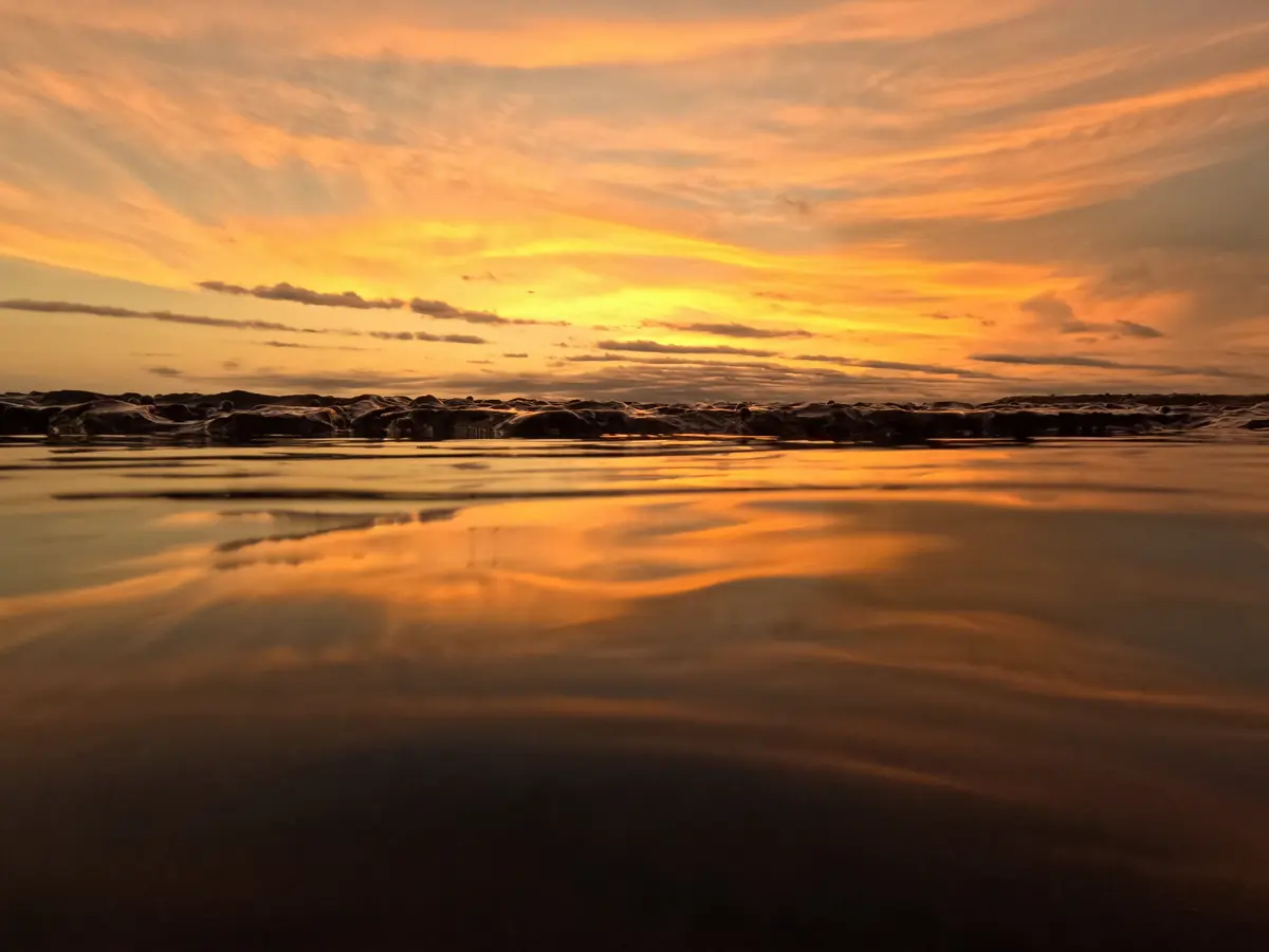 An orange sunset reflected in wet sand at Mar Azul