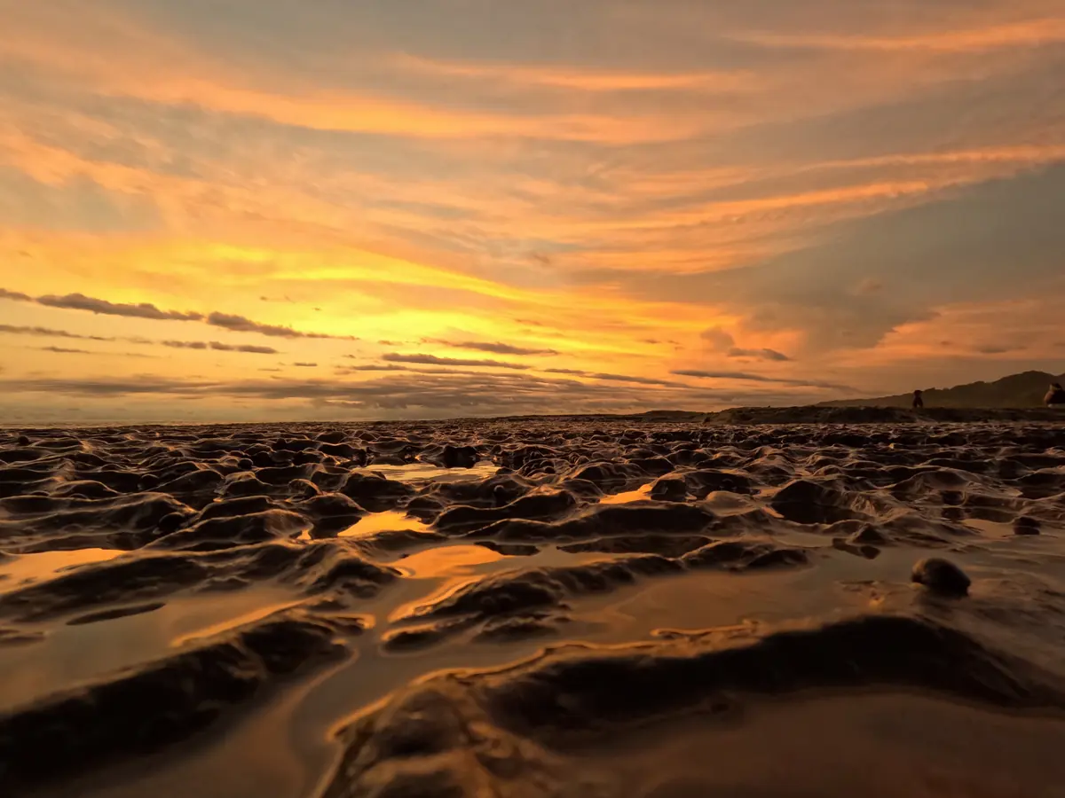 Sunset over the rocks at low tide on Mar Azul beach, near Santa Teresa