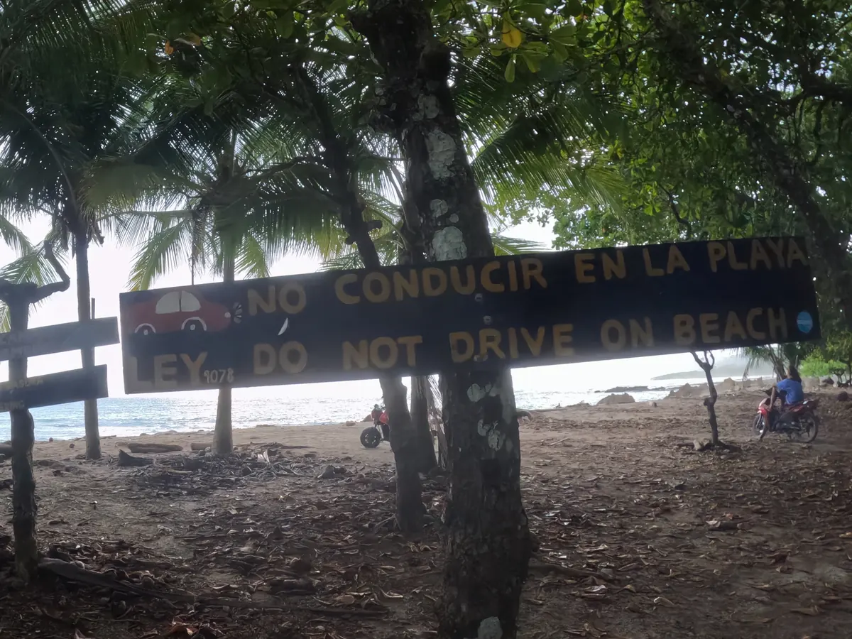 A 'No conducir en la playa' sign marking where ATV access ends and the beach begins near Santa Teresa